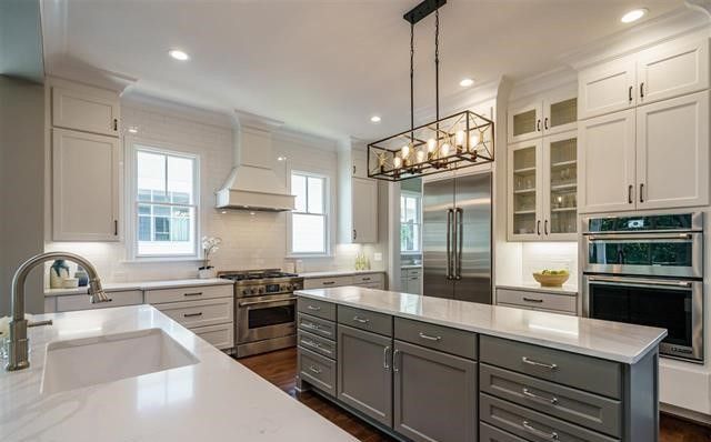 A kitchen with white cabinets and stainless steel appliances and a large island in the middle.