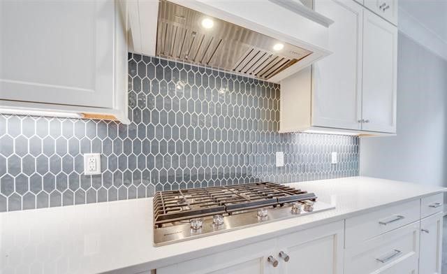 A kitchen with white cabinets and a stove top oven.