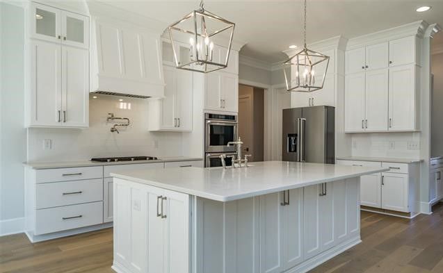 A kitchen with white cabinets , stainless steel appliances , and a large island.