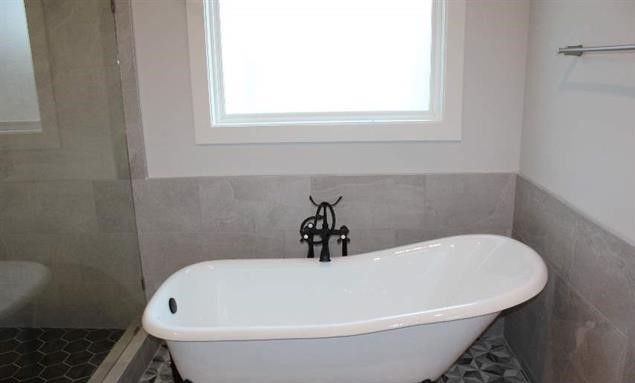 A white bathtub is sitting in a bathroom next to a window.
