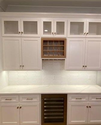 A kitchen with white cabinets and a wine cooler.