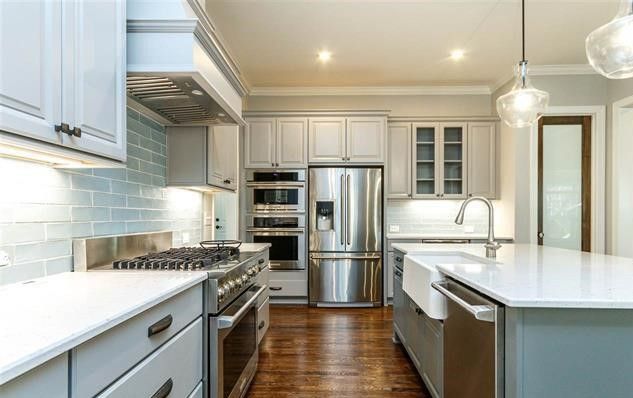 A kitchen with stainless steel appliances and white cabinets.