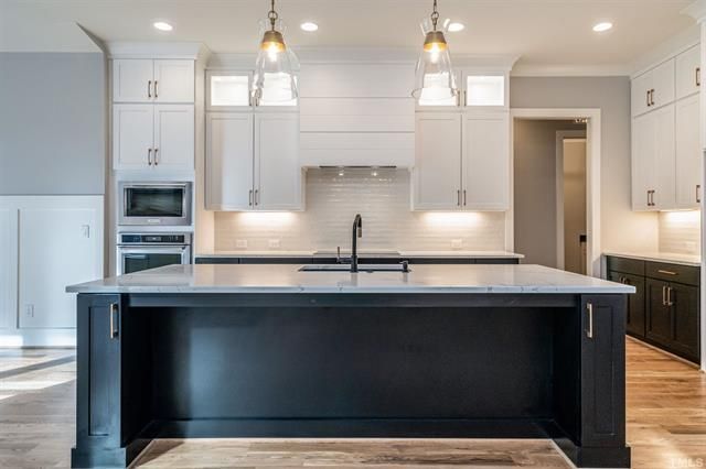 A kitchen with white cabinets and a black island.