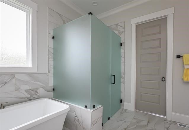 A bathroom with a bathtub and a shower stall with a frosted glass door.