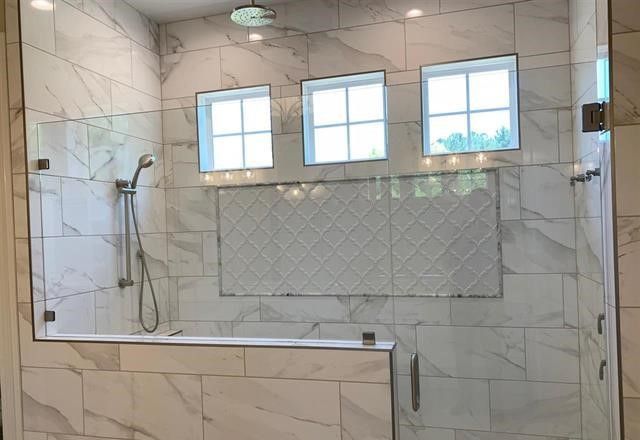 A bathroom with marble tiles and a walk in shower with a glass door.