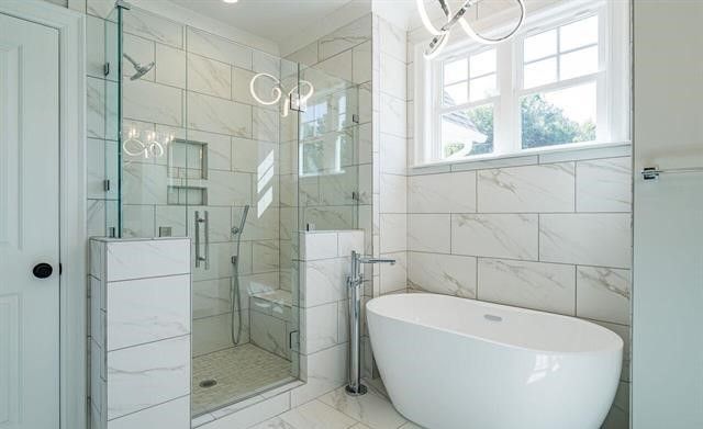 A bathroom with a tub , shower , sink and window.
