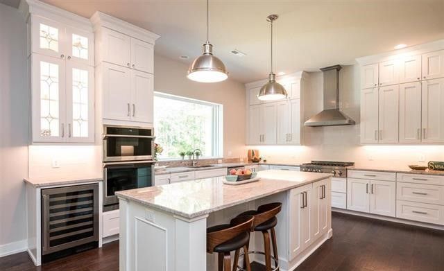 A kitchen with white cabinets , stainless steel appliances , and a large island.
