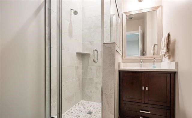 A bathroom with a walk in shower , sink and mirror.