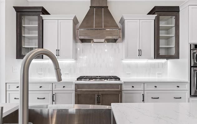 A kitchen with white cabinets , stainless steel appliances , a sink and a stove.