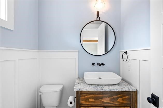 A bathroom with a toilet , sink and mirror.