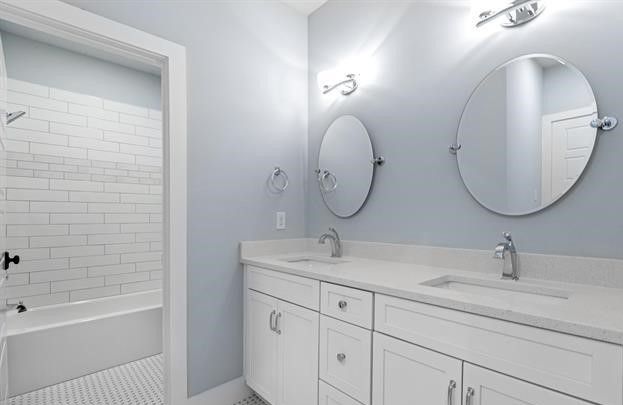 A bathroom with two sinks , two mirrors and a shower.