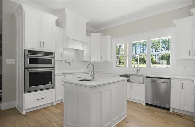 A kitchen with white cabinets , stainless steel appliances , and a large island.