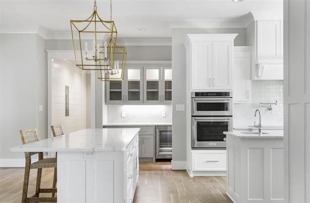 A kitchen with white cabinets , stainless steel appliances , and a large island.