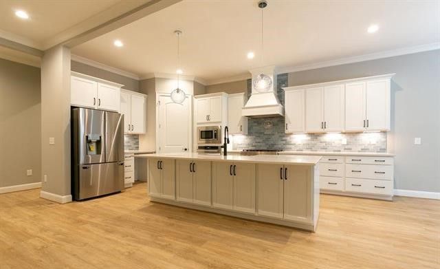 A kitchen with white cabinets , stainless steel appliances , and a large island.