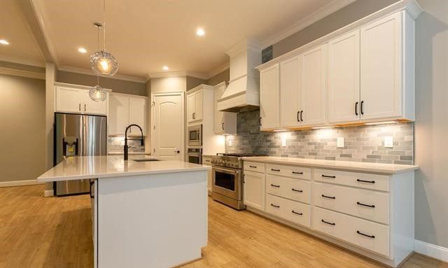 A kitchen with white cabinets , stainless steel appliances , and a large island.