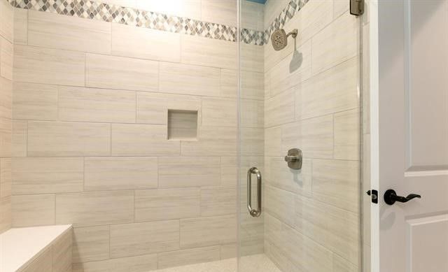 A bathroom with a walk in shower with a glass door.