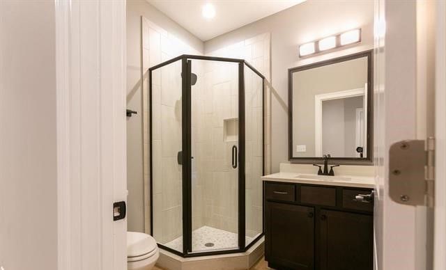 A bathroom with a shower , sink , mirror and toilet.