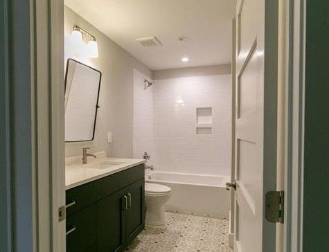 A bathroom with a sink , toilet , tub and mirror.