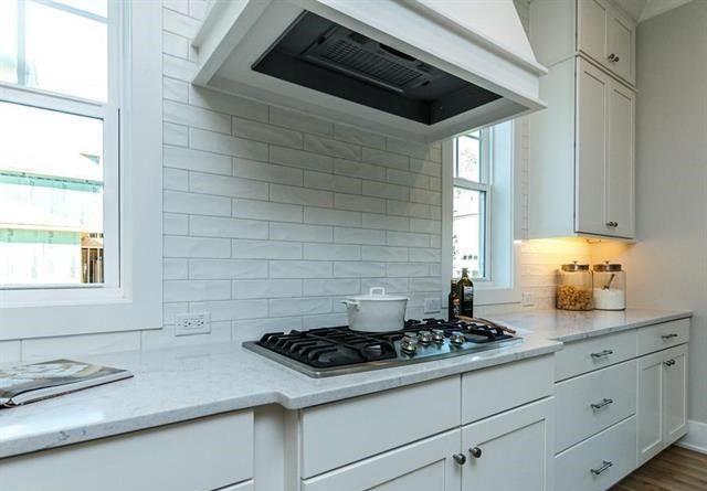 A kitchen with white cabinets and a stove top oven.