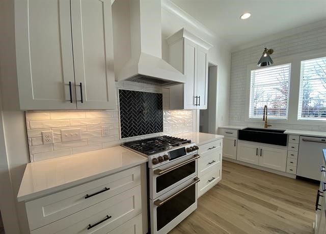 A kitchen with white cabinets , a stove and a sink.