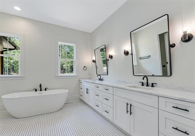 A bathroom with two sinks , a tub , and two mirrors.
