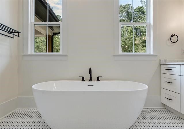 A bathroom with a bathtub and two windows.