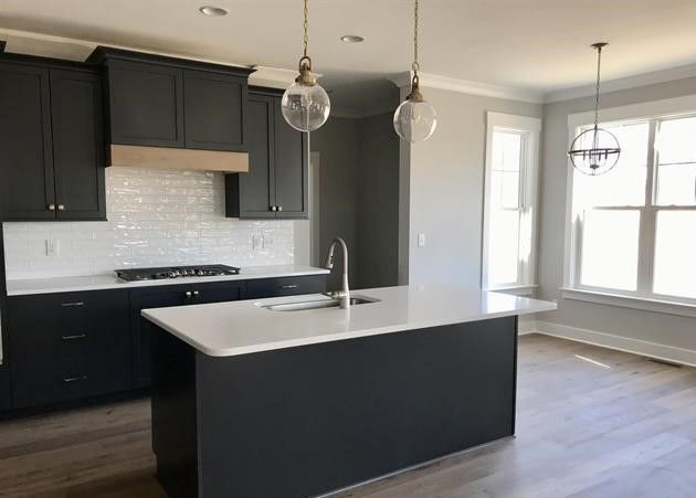 A kitchen with black cabinets and a large island in the middle