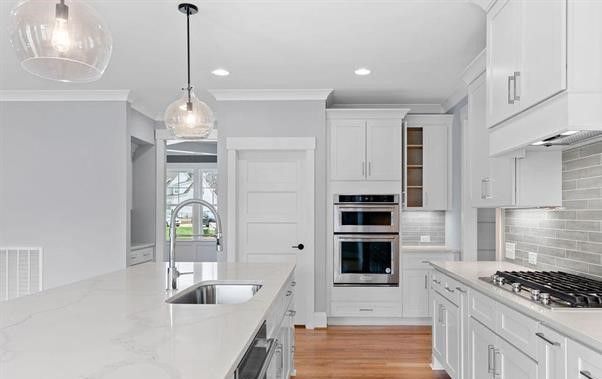 A kitchen with white cabinets , stainless steel appliances , and a large island.