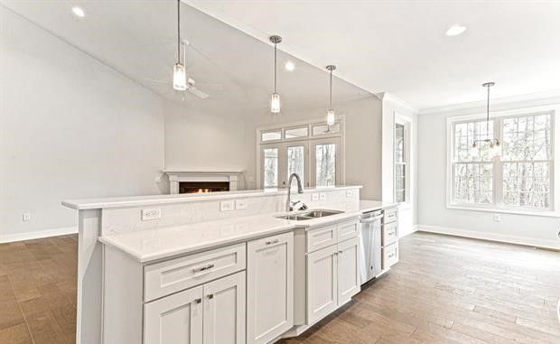 A kitchen with white cabinets , a sink , and a fireplace.