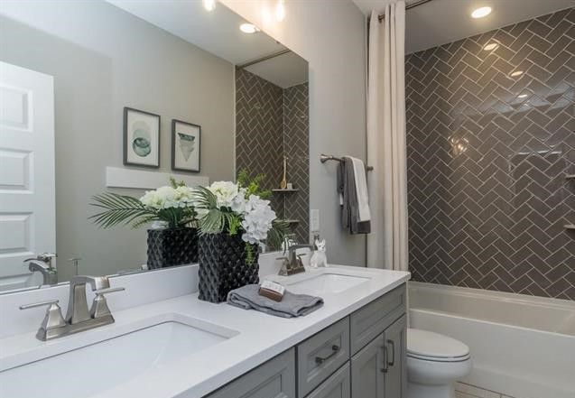 A bathroom with two sinks , a toilet , and a large mirror.