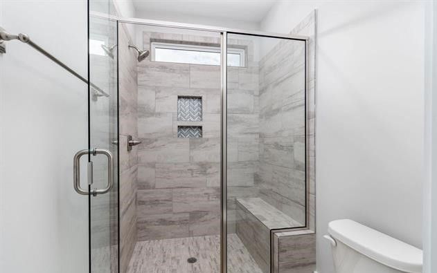 A bathroom with a walk in shower and a toilet.