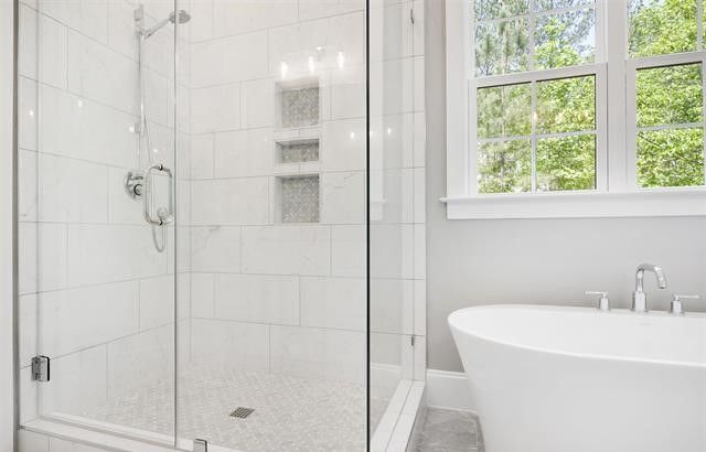 A bathroom with a tub , shower , and window.