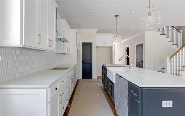 A kitchen with white cabinets and a large island.