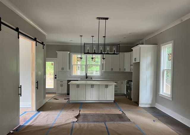 A kitchen with white cabinets and a large island in a house under construction.
