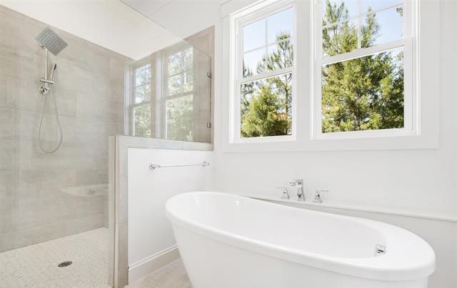 A bathroom with a tub , shower , and window.