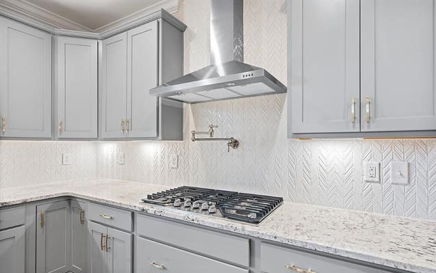 A kitchen with white cabinets , granite counter tops , a stove top oven and a hood.