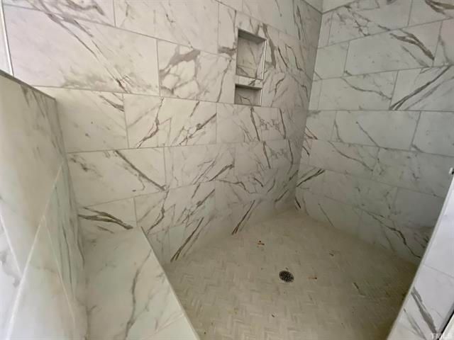 A bathroom with marble tiles and a walk in shower.