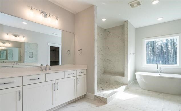 A bathroom with two sinks , a tub , a shower and a large mirror.