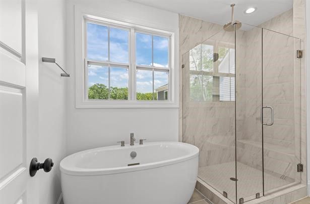 A bathroom with a tub , shower , and window.