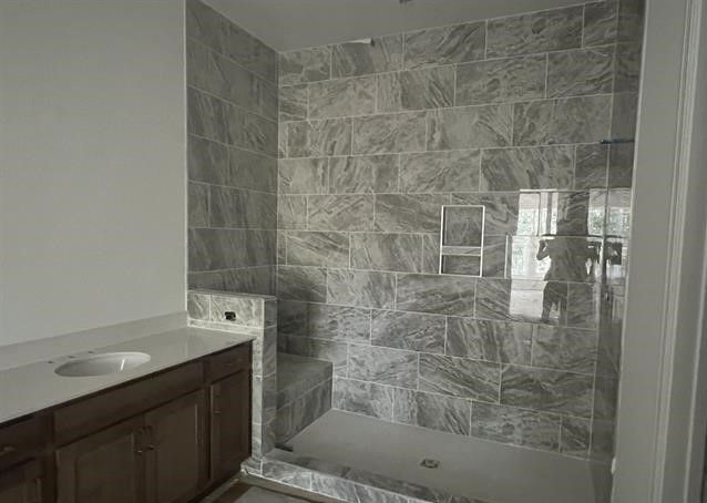 A bathroom with a walk in shower and a sink.