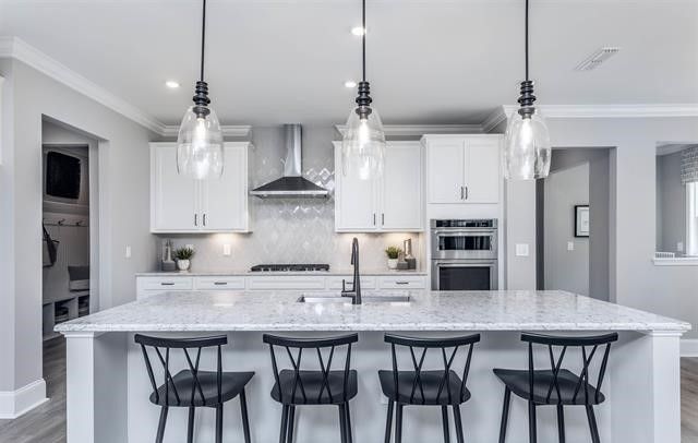 A kitchen with white cabinets and black chairs and a large island