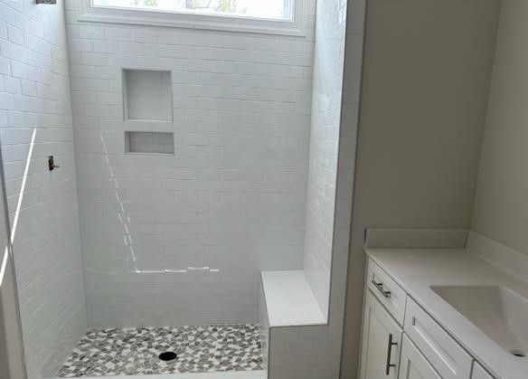 A bathroom with a walk in shower and a sink.