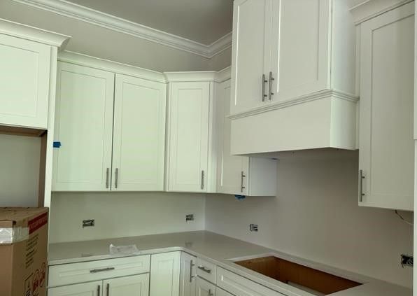 A kitchen with white cabinets and a stove top oven.