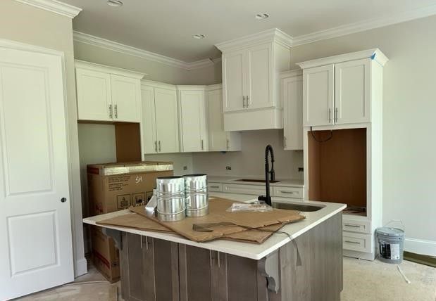 A kitchen under construction with white cabinets and a large island