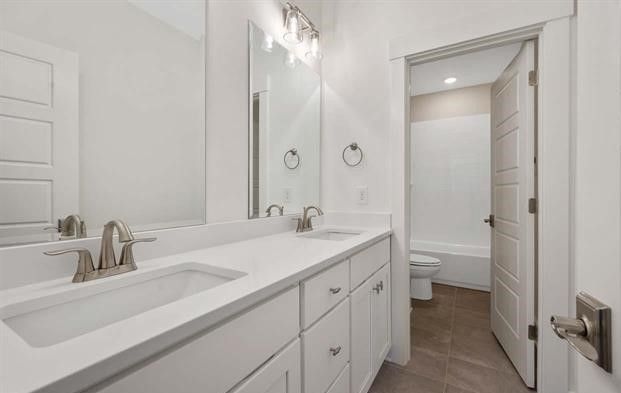 A bathroom with two sinks , a toilet , and a mirror.