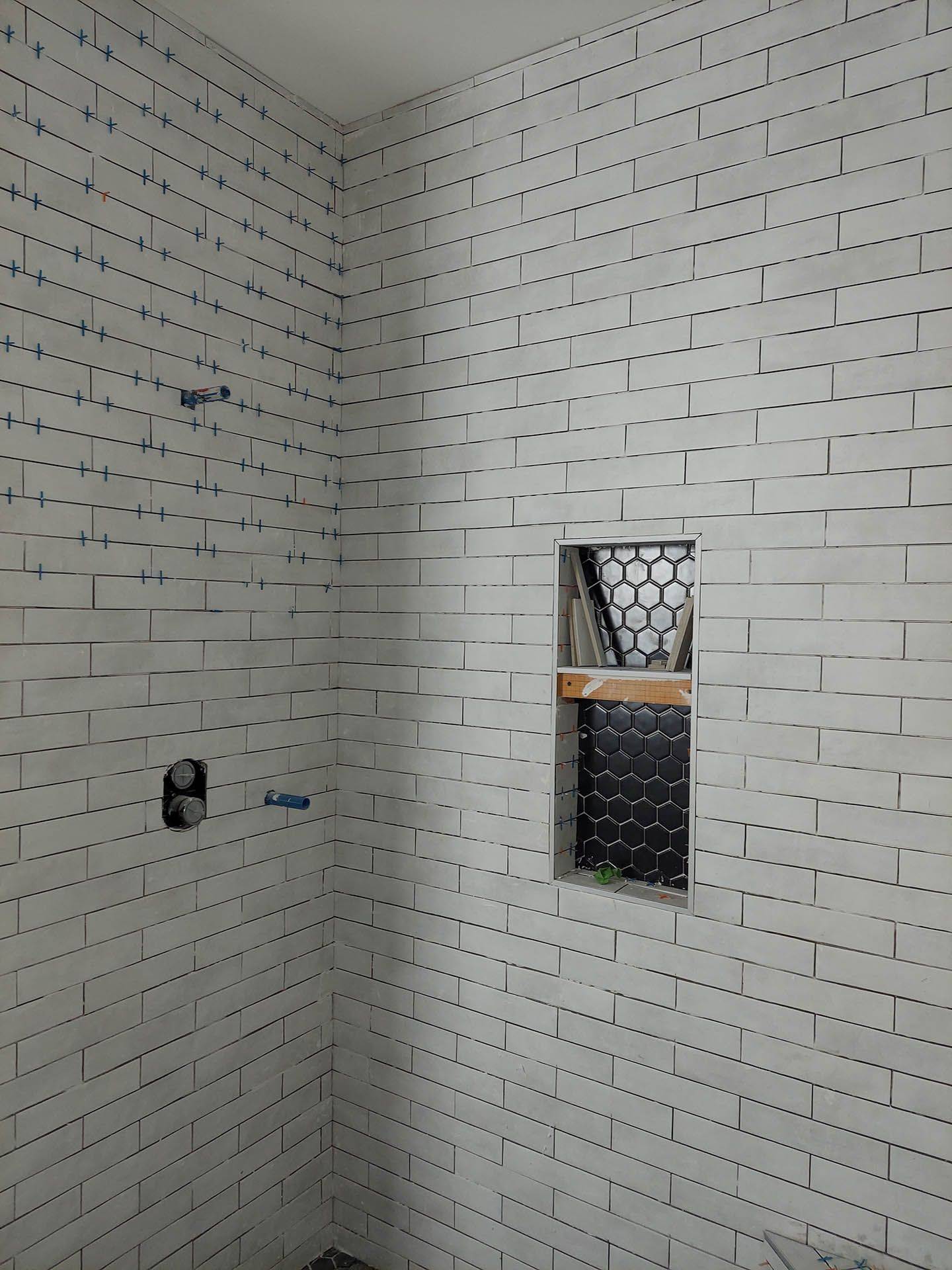 A shower stall with a brick wall and a window.