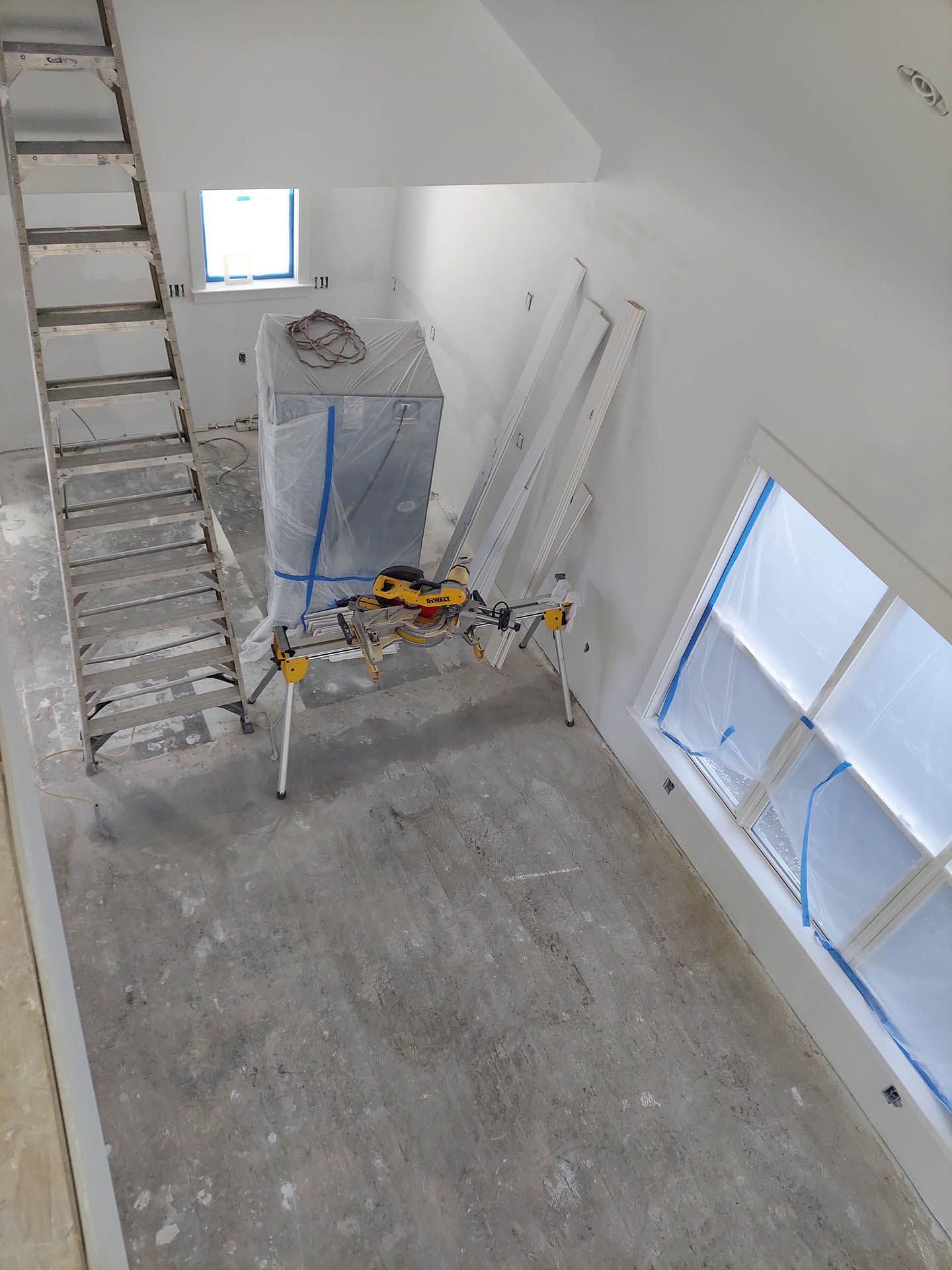 An aerial view of a room with a ladder and a table.