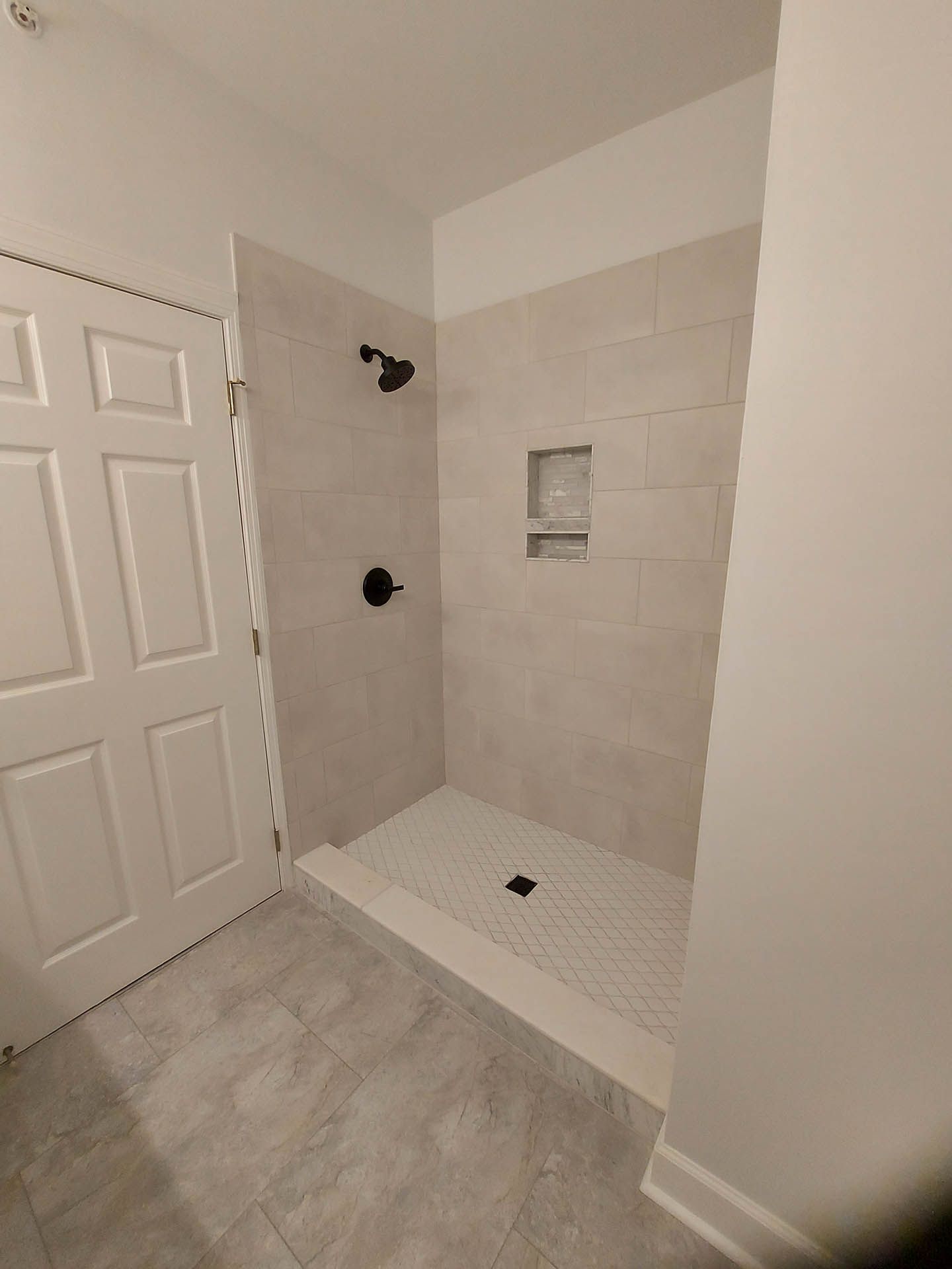 A bathroom with a walk in shower and a white door.