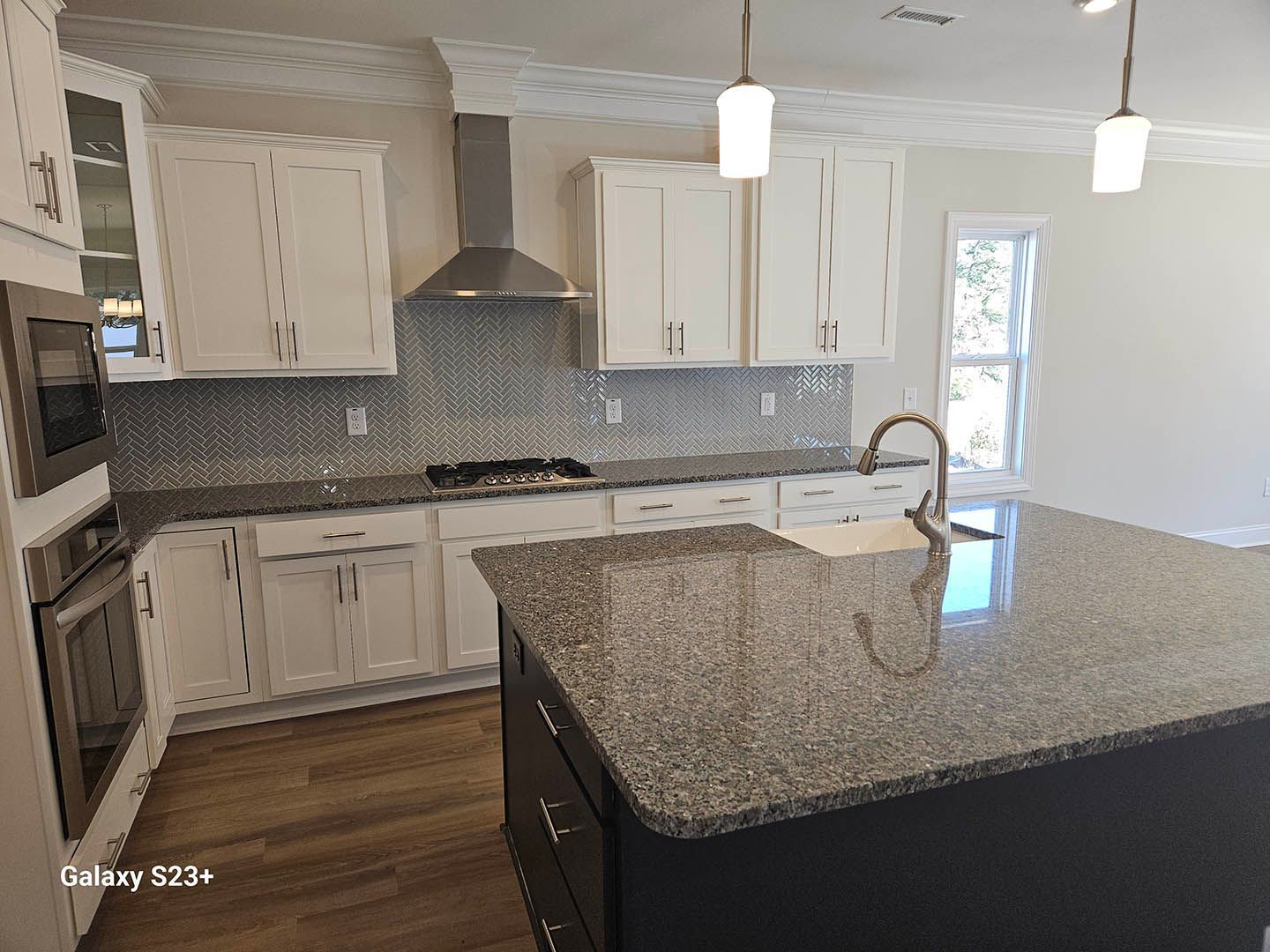 A kitchen with granite counter tops and white cabinets.