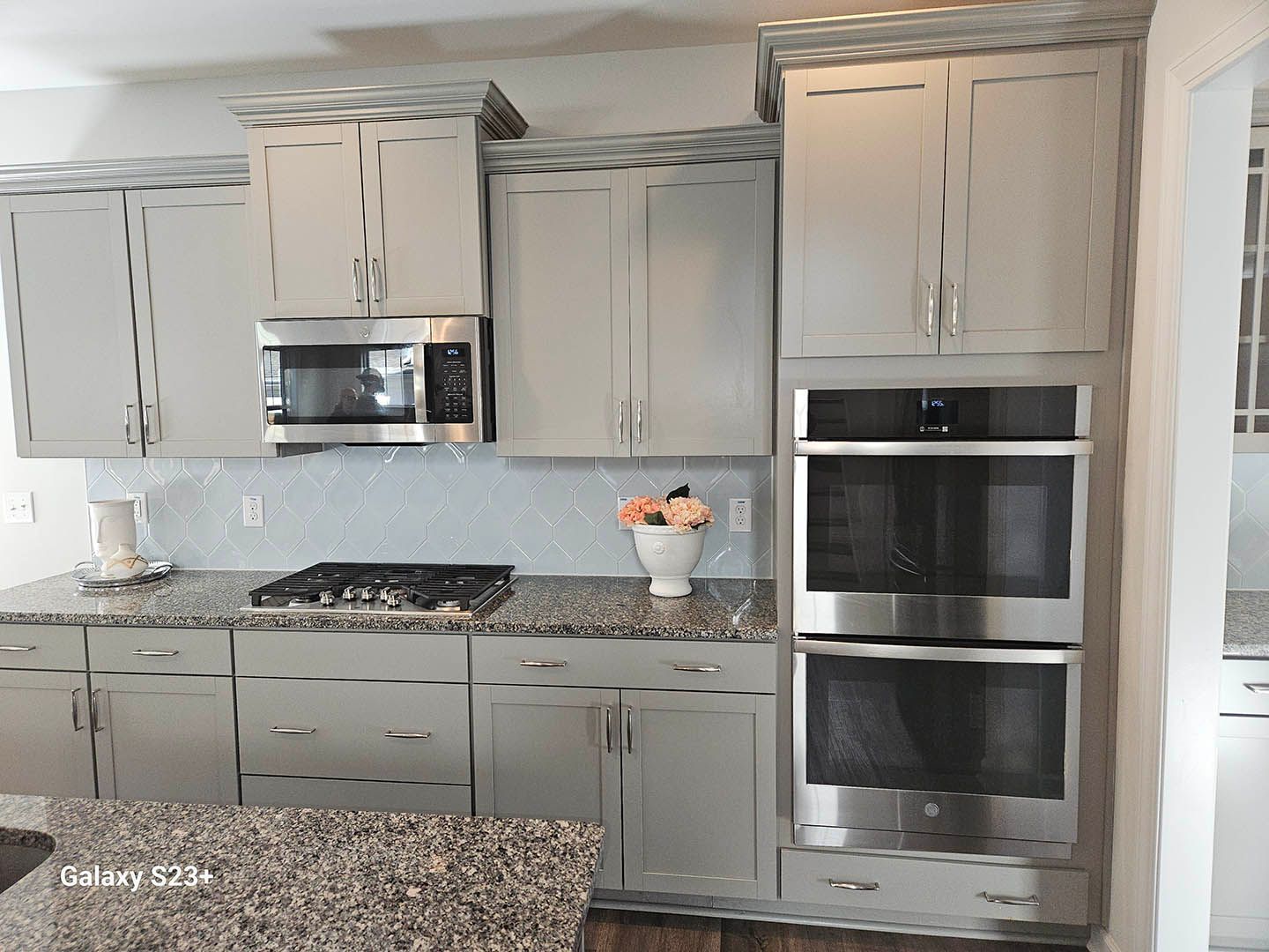 A kitchen with gray cabinets and stainless steel appliances